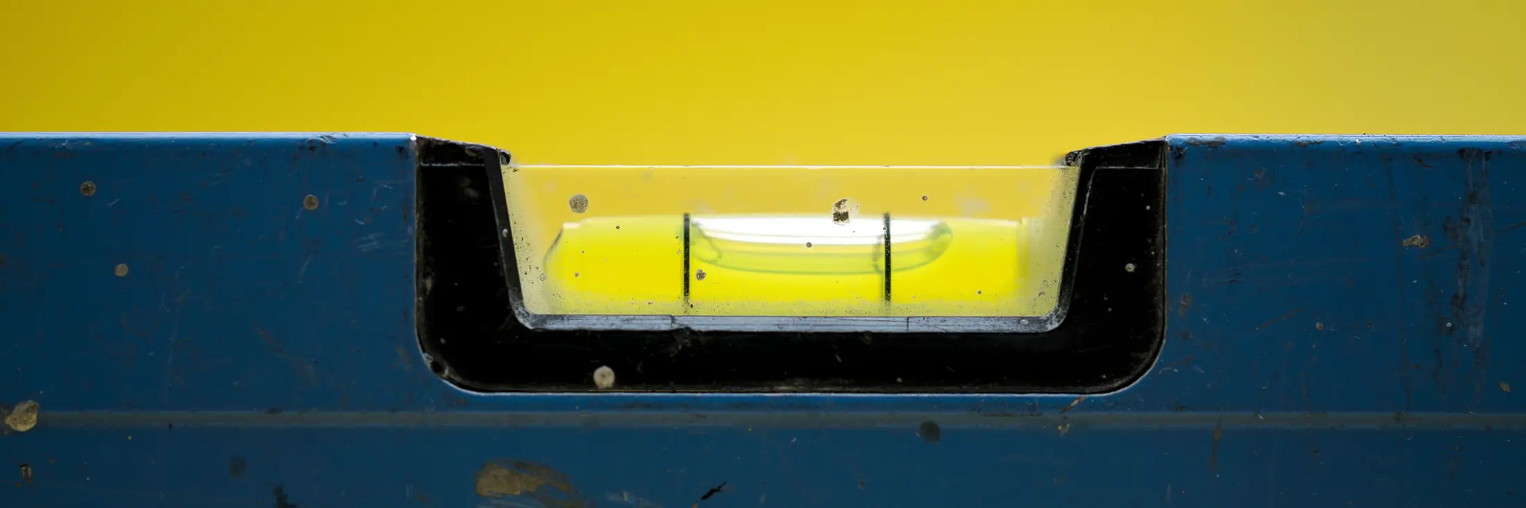 Close-up of a blue spirit level with the bubble centered between the lines.